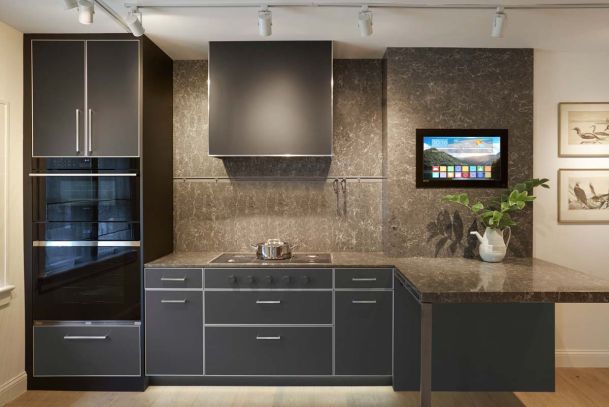 dark grey cabinets in grey kitchen with tv screen on wall