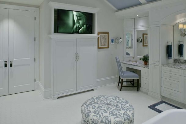 master bathroom with television on wall with white cabinets